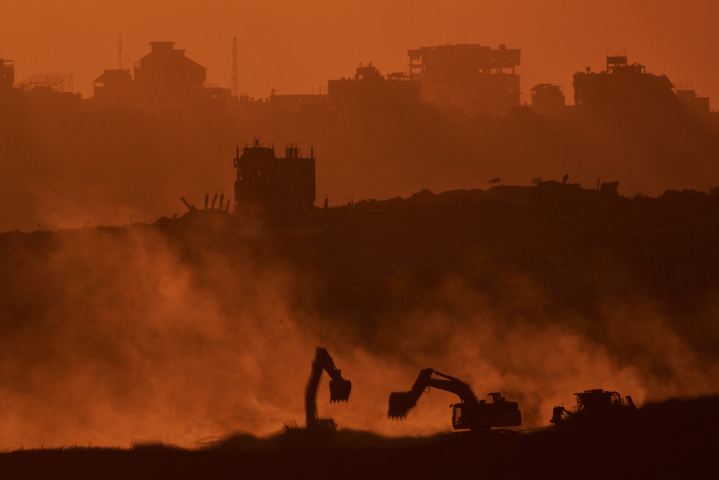 Israeli excavators work in the Gaza Strip as the sun sets, seen from southern Israel, Tuesday, Oct. 14, 2025. (AP Photo/Leo Correa)