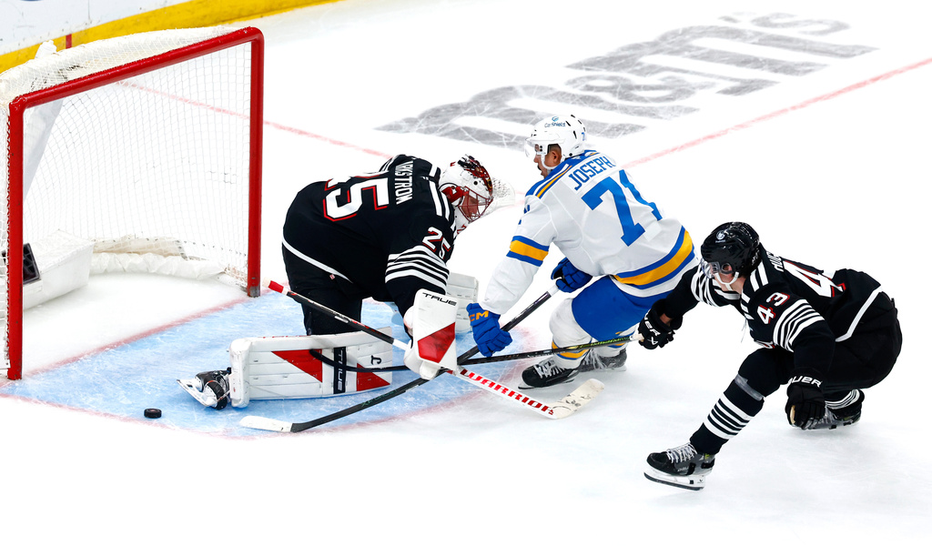 New Jersey Devils goaltender Jacob Markstrom and defenseman Luke Hughes defend against St. Louis Blues right wing Mathieu Joseph during the third period of an NHL hockey game, Wednesday, Nov. 26, 2025, in Newark, N.J. (AP Photo/Noah K. Murray)