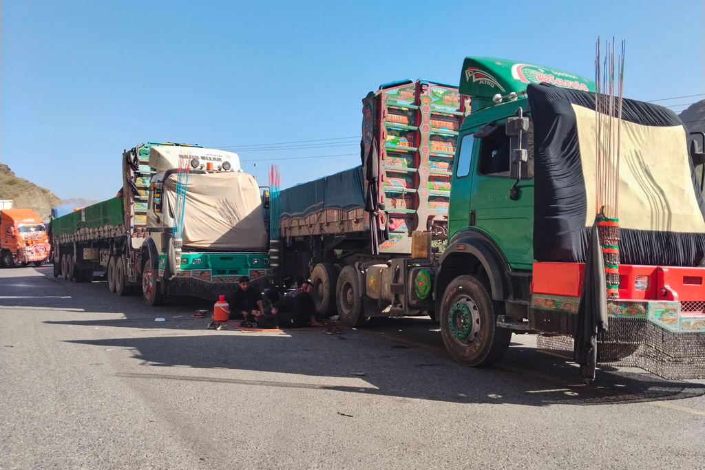 Drivers sit beside trucks loaded with goods for Afghanistan park along a highway following border closed due to Afghan and Pakistani forces exchange cross border firing, in Landi Kotel, in the district Khyber, Pakistan, Monday, Oct. 13, 2025. (AP Photo/Qazi Rauf)