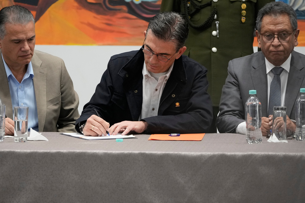 Bolivian President Rodrigo Paz signs legislation approved by Congress establishing the legal framework for a state of emergency at the government palace, accompanied by his Defense Minister Ernesto Justiniano, left, and Minister of Government Marco Antonio Oviedo in La Paz, Bolivia, Monday, June 8, 2026. (AP Photo/Juan Karita)