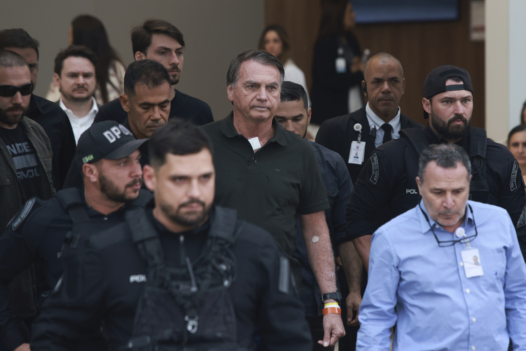 Former President Jair Bolsonaro, center, temporarily allowed out of house arrest for medical treatment, departs a hospital in Brasilia, Brazil, Sunday, Sep. 14, 2025. (AP Photo/Luis Nova)