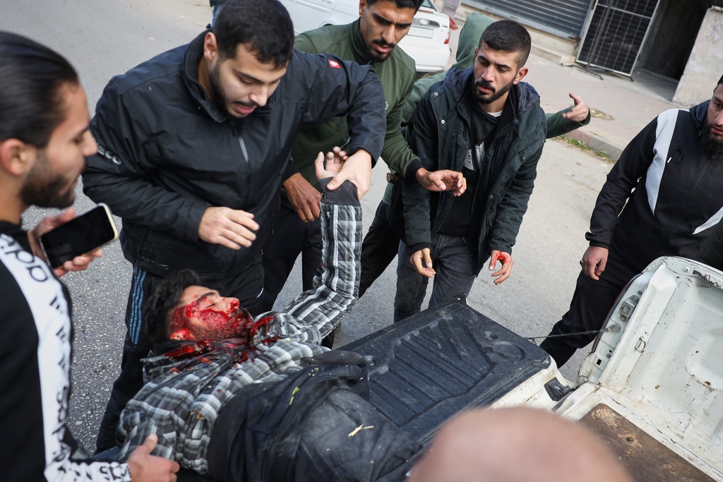 A man seriously injured by a thrown stone is taken away from the area after clashes erupted between Alawite protesters from the Alawite religious minority and counterprotesters, two days after a bomb in an Alawite mosque in Homs killed eight people and wounded 18 during Friday prayers, in Latakia, Syria's coastal region, Sunday, Dec. 28, 2025. (AP Photo/Omar Albam)