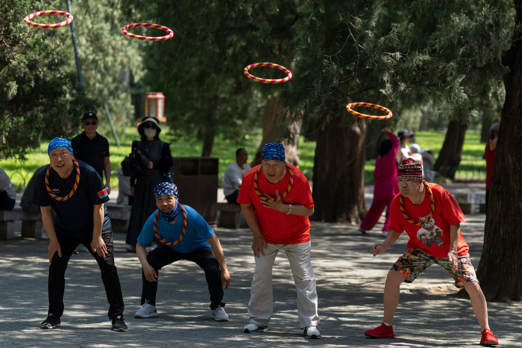 Men catch hoops with their heads in a traditional game of Qiankun hoops played at the Temple of Heaven park in Beijing, Monday, May 11, 2026. (AP Photo/Ng Han Guan)
