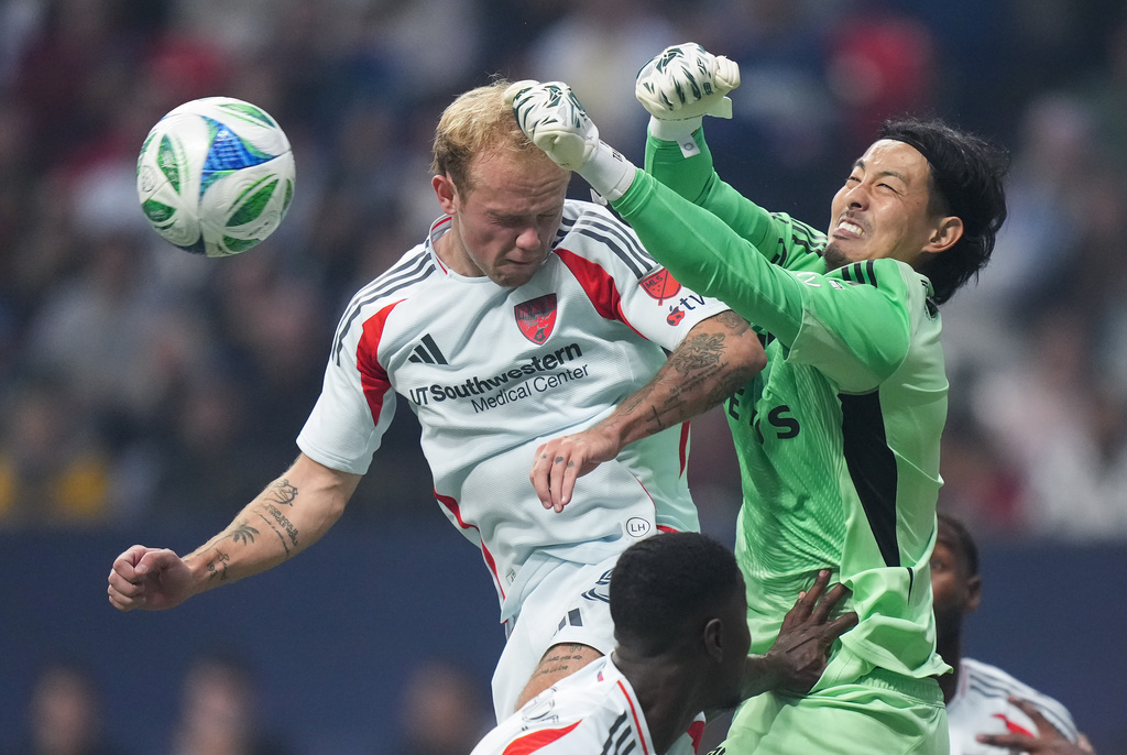 Vancouver Whitecaps' goalkeeper Yohei Takaoka, right, punches the ball away from FC Dallas' Samuel Sarver during the first half of an MLS soccer match, in Vancouver, on Saturday, October 18, 2025. (Darryl Dyck/The Canadian Press via AP)