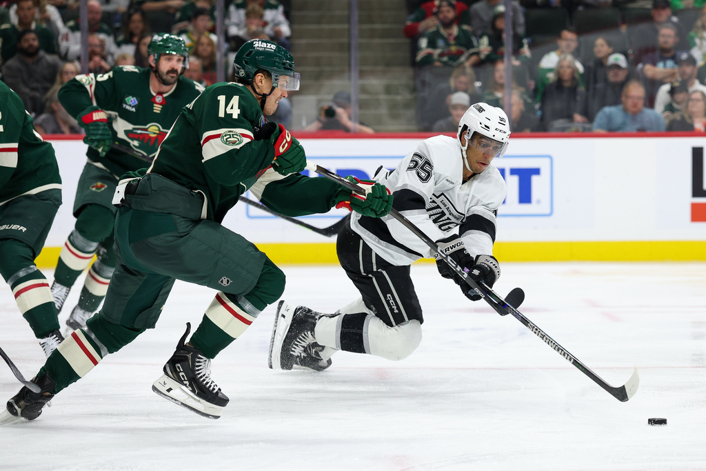 Los Angeles Kings right wing Quinton Byfield, right, and Minnesota Wild center Joel Eriksson Ek (14) compete for the puck during the second period of an NHL hockey game Monday, Oct. 13, 2025, in St. Paul, Minn. (AP Photo/Matt Krohn)