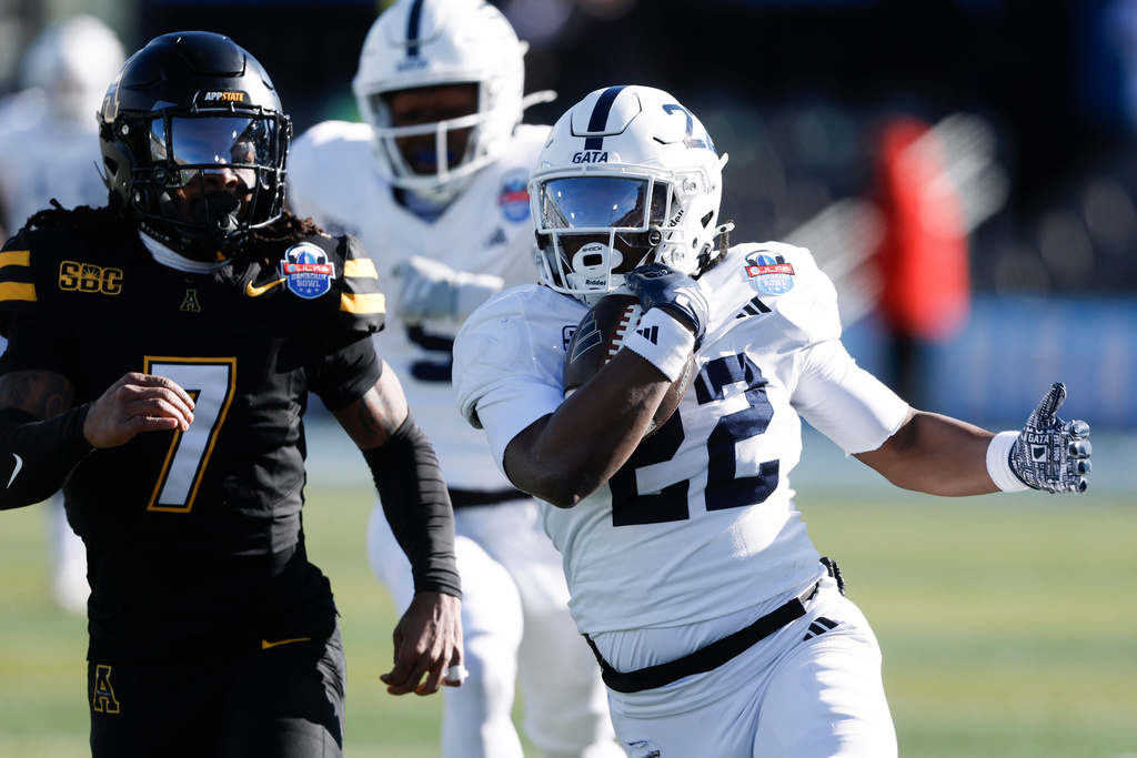 Georgia Southern running back OJ Arnold (22) carries the ball as Appalachian State defensive back Jordan Favors (7) pursues during the first half of the Birmingham Bowl NCAA college football game, Monday, Dec. 29, 2025, in Birmingham. (AP Photo/Butch Dill)