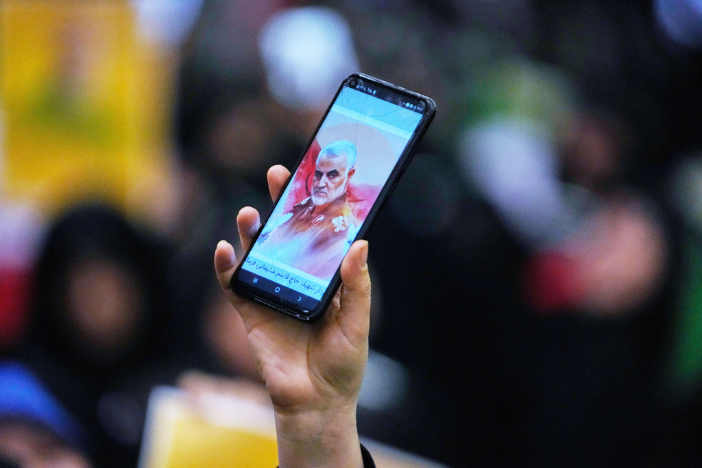 A woman shows a portrait of the late commander of Iran's Revolutionary Guard expeditionary Quds Force, Gen. Qassem Soleimani, who was killed in a U.S. drone attack in 2020 in Iraq, on her smartphone during a ceremony commemorating his death anniversary at the Imam Khomeini grand mosque in Tehran, Iran, Thursday, Jan. 1, 2026. (AP Photo/Vahid Salemi)
