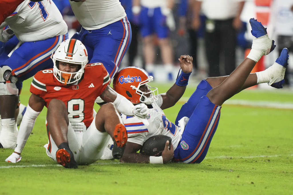 Florida quarterback DJ Lagway (2) falls to the field after being sacked by Miami defensive back Jakobe Thomas (8) during the first half of an NCAA college football game, Saturday, Sept. 20, 2025, in Miami Gardens, Fla. (AP Photo/Lynne Sladky)