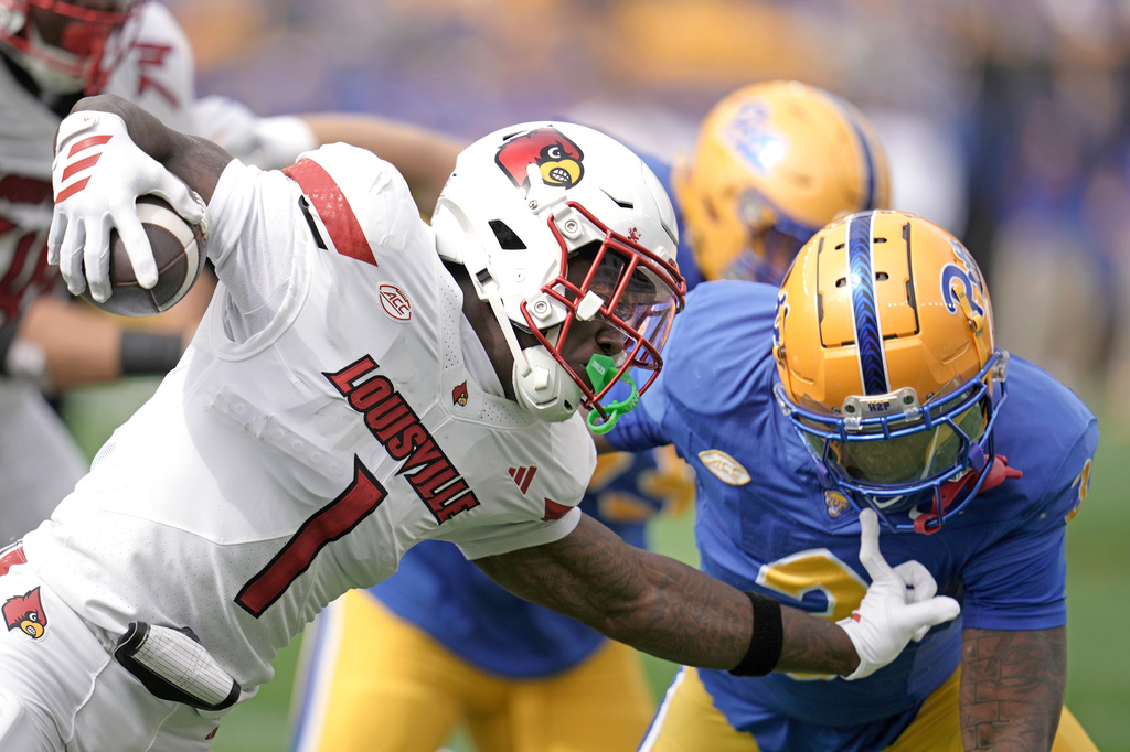 FILE - Louisville Cardinals running back Isaac Brown (1) stiff arms Pittsburgh linebacker Rasheem Biles (3) on a carry during the first half of an NCAA college football game in Pittsburgh, Sept. 27, 2025. (AP Photo/Gene J. Puskar, File)