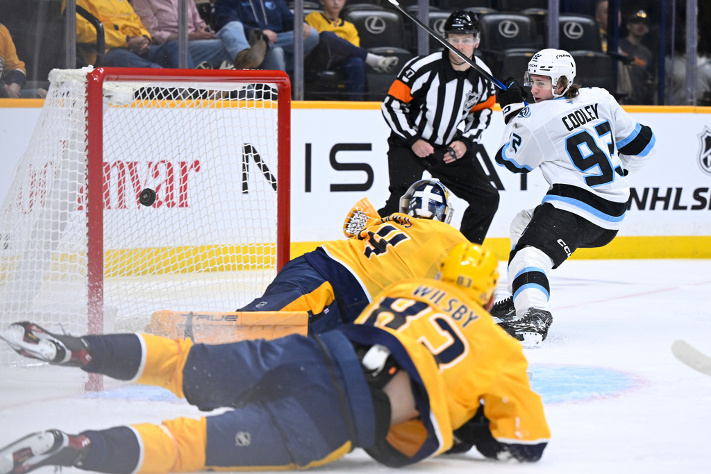 Utah Mammoth center Logan Cooley (92) scores a goal as Nashville Predators goaltender Juuse Saros and defenseman Adam Wilsby (83) defend during the first period of an NHL hockey game Saturday Oct. 11, 2025, in Nashville, Tenn. (AP Photo/John Amis)