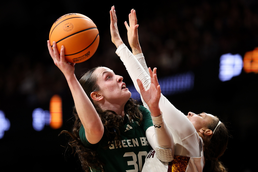 Green Bay forward Jenna Guyer, left, goes up for a shot as Minnesota guard Amaya Battle, right, defends during the first half in the first round of the NCAA college basketball tournament Friday, March 20, 2026, in Minneapolis. (AP Photo/Matt Krohn)