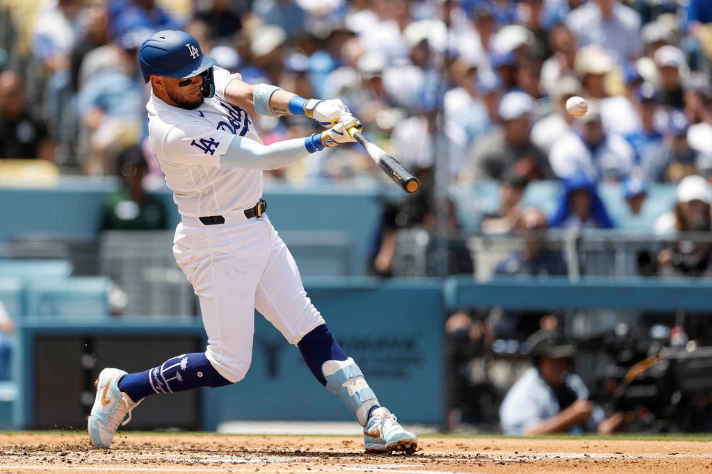 Los Angeles Dodgers' Miguel Rojas hits a two-run double, scoring teammates Kyle Tucker and Teoscar Hernandez, during the first inning of a baseball game against the Chicago Cubs, Sunday, April 26, 2026, in Los Angeles. (AP Photo/Caroline Brehman)