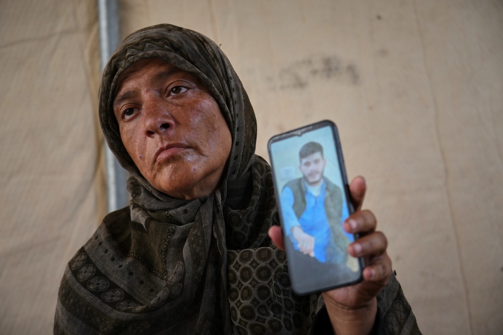 Fadwa al-Ghalban holds a cellphone showing a photo of her son, Mosaab, at her tent in Muwasi, along Gaza's southern coast, Oct. 3, 2025. She has had no word from him since July, when his cousins last saw him near their house as an Israeli strike destroyed it in the southern town of Maan. (AP Photo/Jehad Alshrafi)