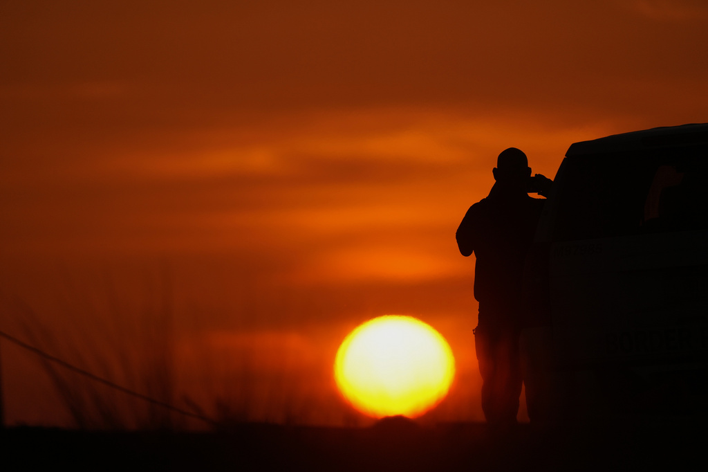 A U.S. Border Patrol agent takes a picture of the sunrise next to a section of border wall at the Santa Ana Wildlife Refuge in Alamo, Texas, Tuesday, Aug. 25, 2026. (AP Photo/Eric Gay)