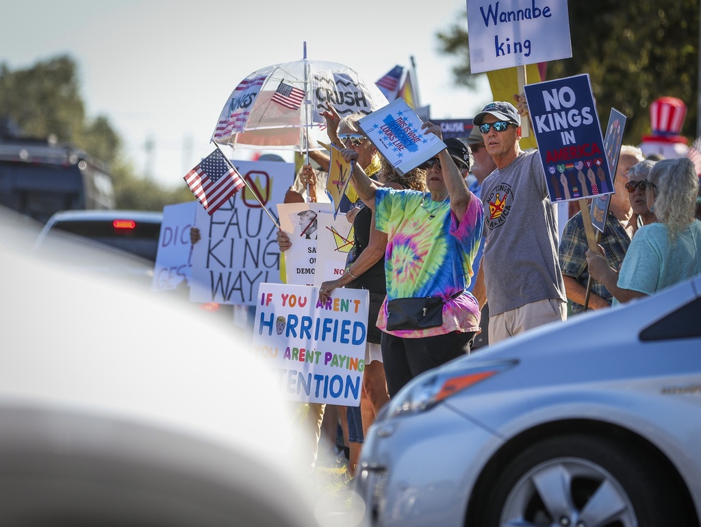 People line Gulf to Bay Boulevard holding signs and waving to traffic during a "No Kings" protest Saturday, Oct. 18, 2025 in Clearwater, Fla. (Chris Urso/Tampa Bay Times via AP)