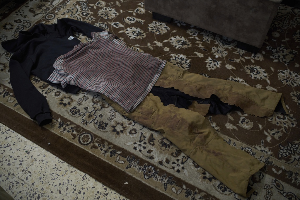 Blood-stained clothes, which Wafa Jazar, 42, says were worn by her 14-year-old son, Ahmad Jazar, when he was shot by Israeli soldiers, are laid out for a photo in a room of their home in the West Bank village of Sebastia, March 11, 2025. (AP Photo/Leo Correa)