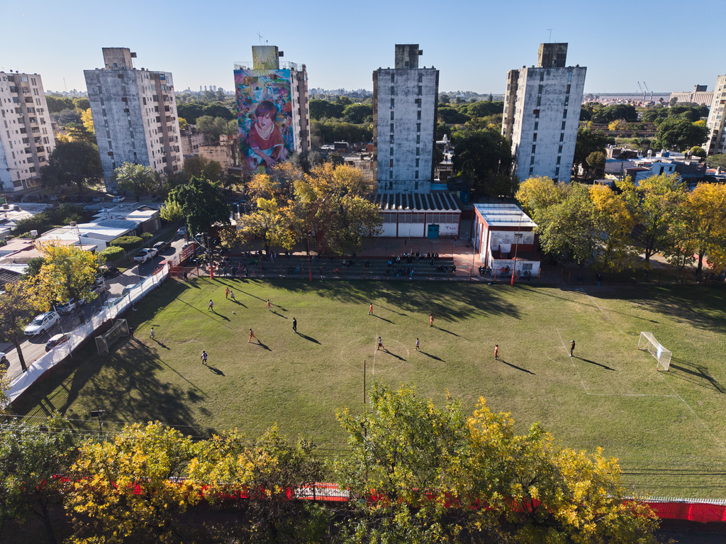 A mural of soccer star Lionel Messi covers the wall of a building as children play a match at the Grandoli club, where Messi played as a child in Rosario, Argentina, Saturday, May 2, 2026. (AP Photo/Rodrigo Abd)