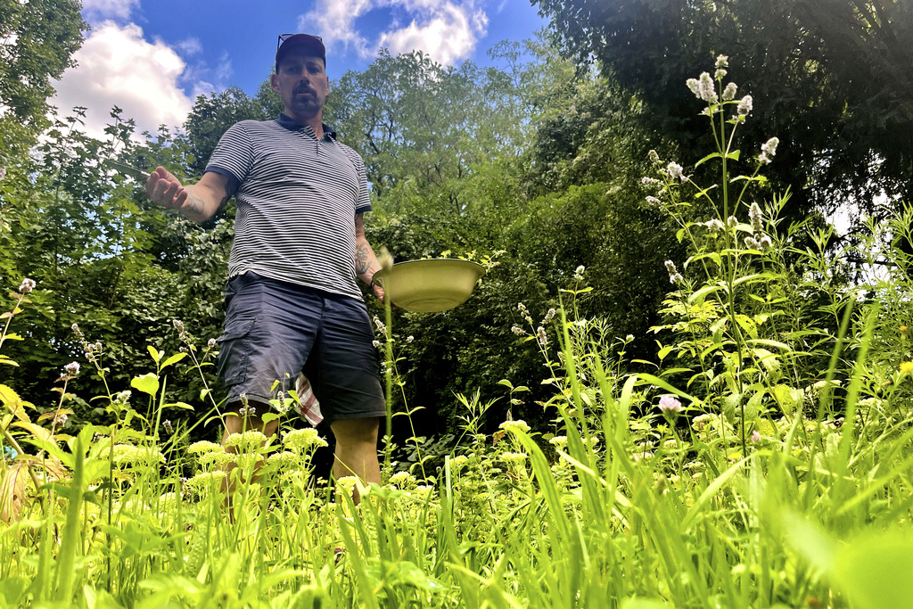 Martin Roetzel, owner of 'The Monk Garden' stands between different plants in Berlin, Germany, Sunday, Aug. 17, 2025. (AP Photo/Fanny Brodersen)