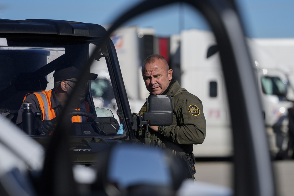 U.S. Border Patrol agent Juan Di Bella talks to a worker during an immigration enforcement operation at a truck stop Monday, Nov. 3, 2025, in Hampshire, Ill. (AP Photo/Erin Hooley)