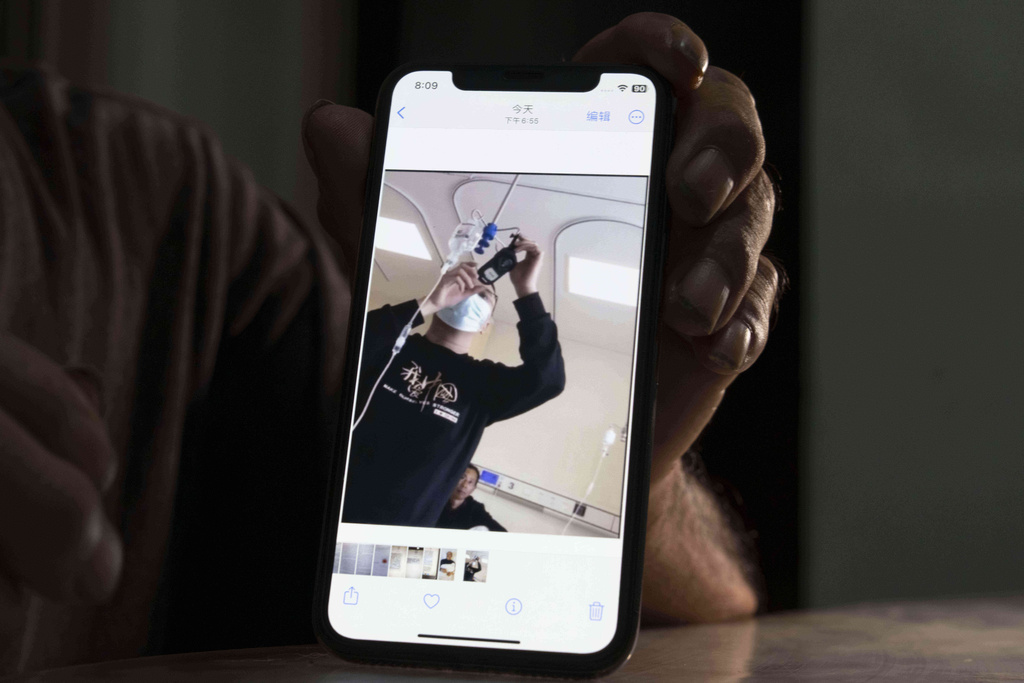 Yang Guoliang shows a March 12, 2024, photo of a police officer hanging a body camera from an IV drip to monitor him in a hospital bed after police beat him with bricks, as he sits in his home in Changzhou in eastern China's Jiangsu Province, Sunday, Sept. 7, 2025. (AP Photo/Ng Han Guan)