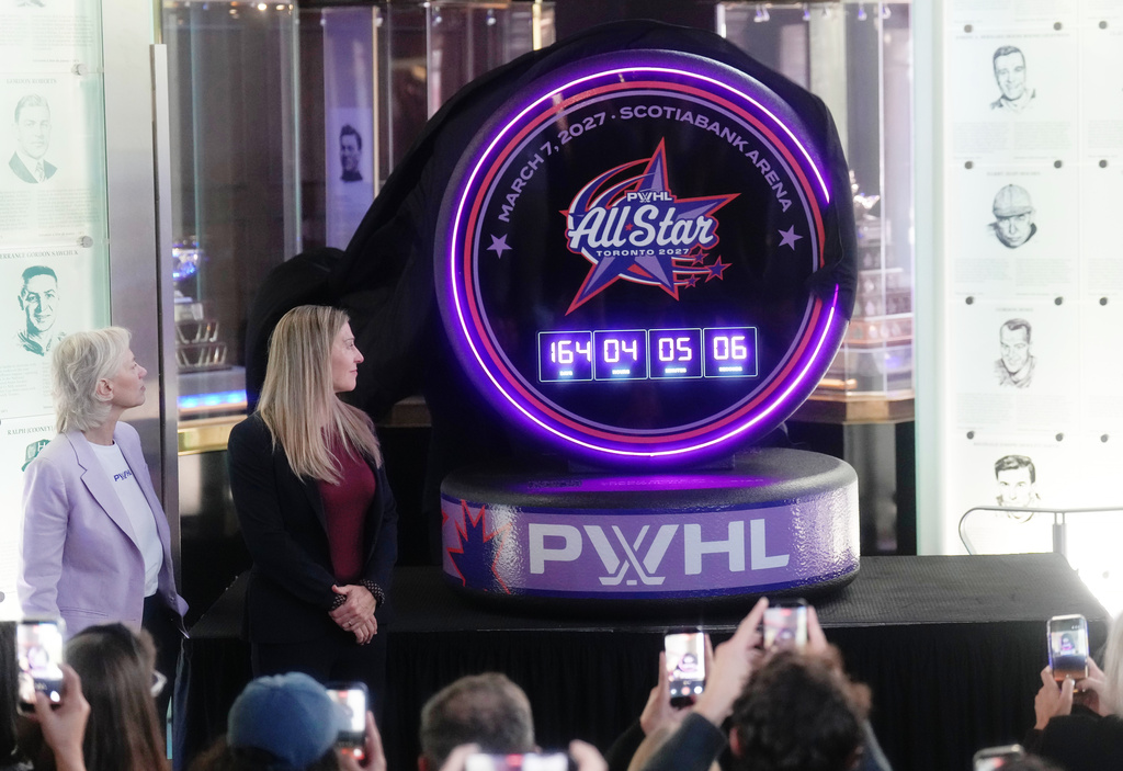 Jayna Hefford, second from left, Executive Vice President of Hockey Operations for the PWHL, and Amy Scheer, left, PWHL Executive Vice President of Business Operations, unveils the logo for the first ever PWHL All-Star-Game which will take place in Toronto next year during a press conference in Toronto, Thursday, Sept. 24, 2026. (Nathan Denette/The Canadian Press via AP)