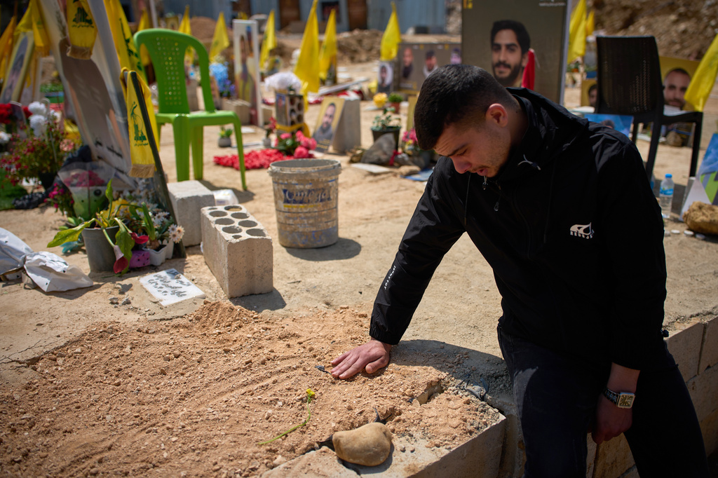 Ahmad Assi, 29, cries on the grave of his friend Hassan Ali Badawi, a paramedic of the Lebanese Red Cross killed in a Israeli strike, during his funeral in Choueifat, Lebanon, Monday, April 13, 2026. (AP Photo/Emilio Morenatti)