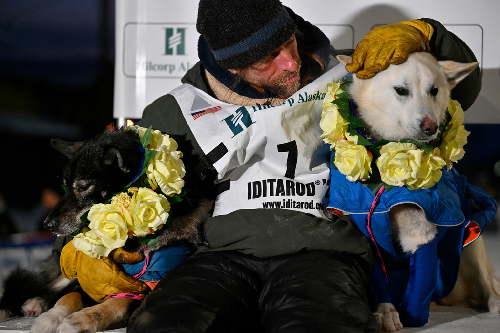 Jessie Holmes poses with his lead dogs Zeus, left, and Polar, after claiming his second straight Iditarod Trail Sled Dog Race championship, in Nome, Alaska, Tuesday March 17, 2026. (Marc Lester/Anchorage Daily News via AP)