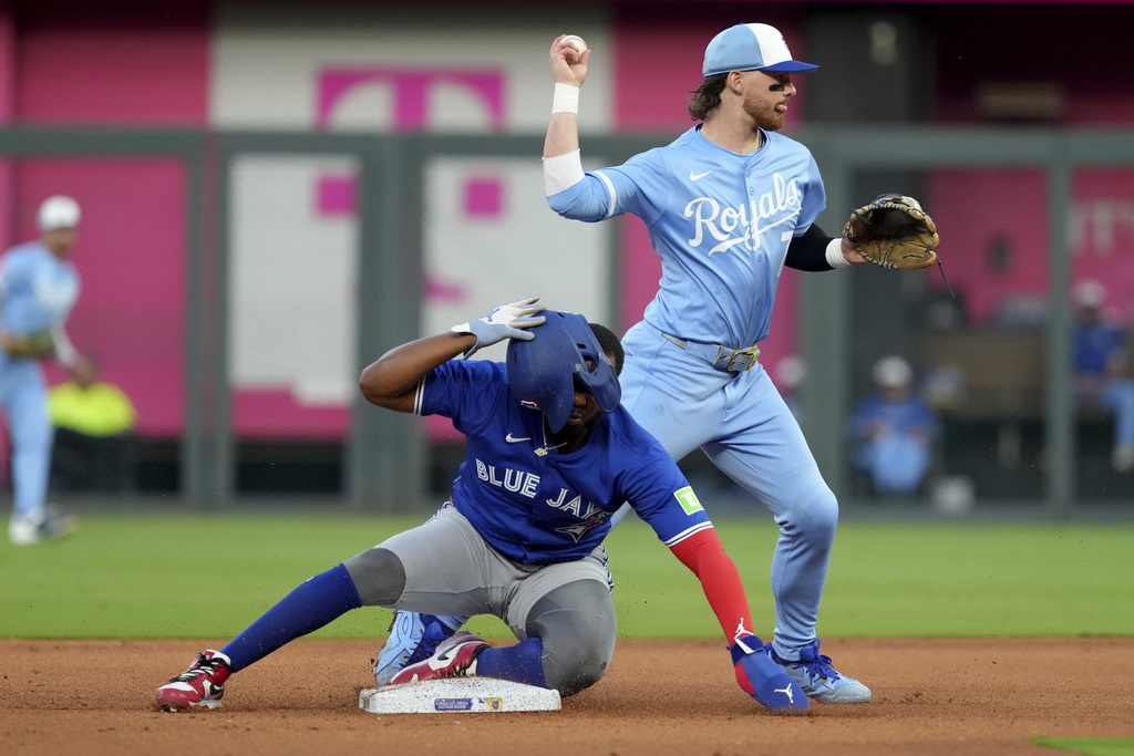 Kansas City Royals shortstop Bobby Witt Jr., top, throws to first base past Toronto Blue Jays' Vladimir Guerrero Jr., bottom, to complete a double play in the fourth inning during a baseball game Saturday Sept. 20, 2025, in Kansas City, Mo. (AP Photo/Ed Zurga)