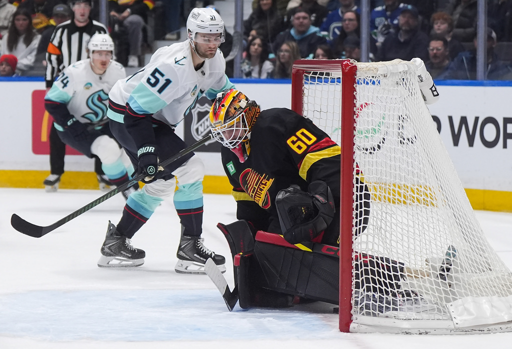 Vancouver Canucks goalie Nikita Tolopilo (60) allows a goal to Seattle Kraken's Bobby McMann, back left, as Shane Wright (51) watches during the first period of an NHL hockey game, in Vancouver, on Saturday, March 14, 2026. (Darryl Dyck/The Canadian Press via AP)