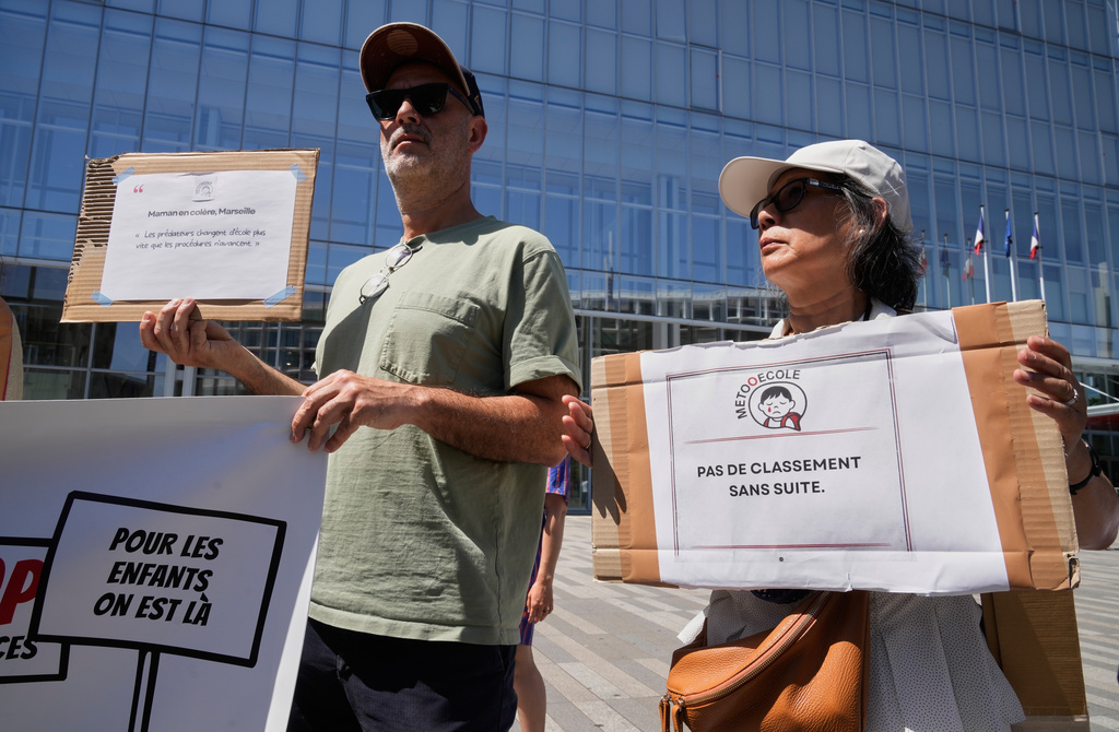 Members and supporters of the #METooEcole (#METooSchool) movement stage a protest to draw attention to a child abuse scandal in France in front of the courthouse in Paris on Tuesday May 26, 2026. One sign reads in French, "Don't drop the case." (AP Photo/Michel Euler)