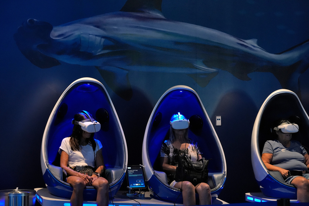 Visitors use virtual reality glasses at the Mote Science Education Aquarium, Monday, Oct. 6, 2025, in Sarasota, Fla. (AP Photo/Chris O'Meara)