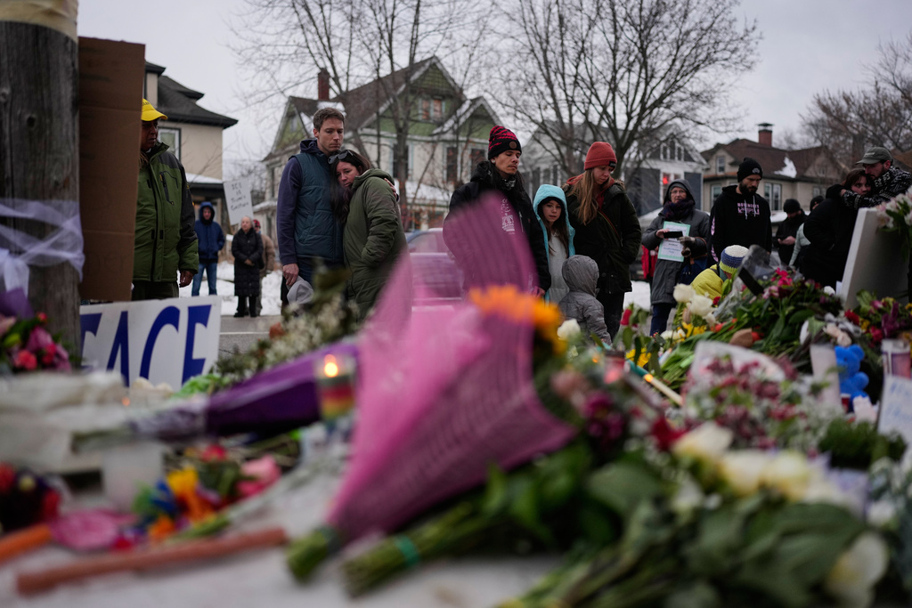 People gather around a makeshift memorial honoring Renee Good, who was fatally shot by an ICE officer the day before, near the site of the shooting in Minneapolis, Thursday, Jan. 8, 2026. (AP Photo/John Locher)
