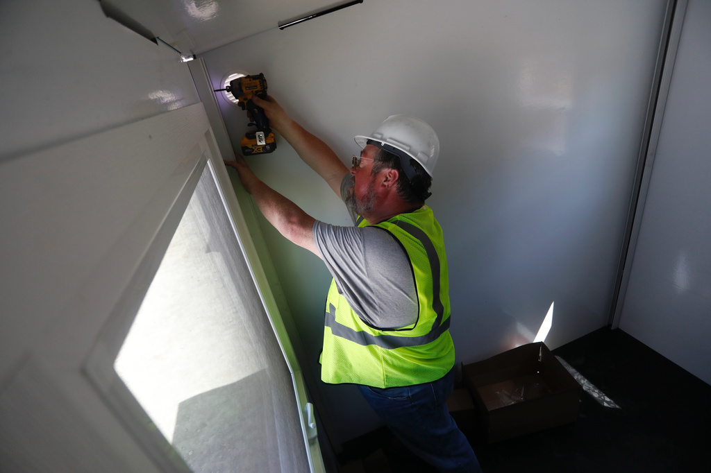 Mason Stanhope works on installing interior elements of a Pallet Shelter unit in in Seattle on Thursday, May 28, 2026. The units, made of composite panels, are part of Seattle Mayor Katie Wilson's plan to expand shelter for the city's homeless. (AP Photo/Manuel Valdes)