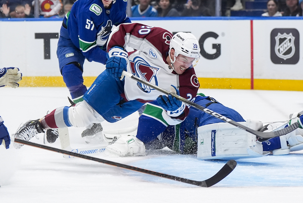 Colorado Avalanche's Ross Colton (20) trips over Vancouver Canucks goalie Kevin Lankinen during the first period of an NHL hockey game in Vancouver, B.C., Sunday, Nov. 9, 2025.(Darryl Dyck/The Canadian Press via AP)