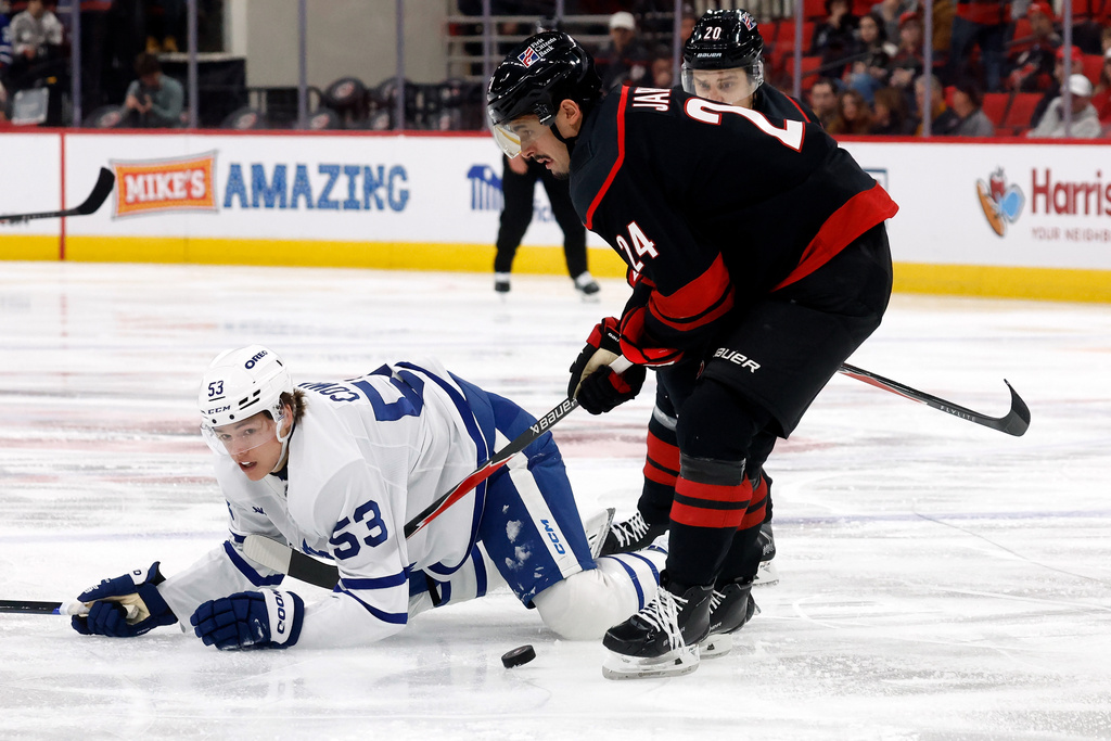 Carolina Hurricanes' Seth Jarvis (24) gathers in the puck after taking it from Toronto Maple Leafs' Easton Cowan (53) during the second period of an NHL hockey game in Raleigh, N.C., Thursday, Dec. 4, 2025. (AP Photo/Karl DeBlaker)