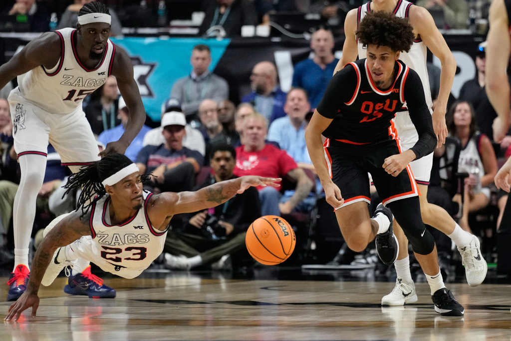 Oregon State forward Isaiah Sy (13) and Gonzaga guard Adam Miller (23) scramble for the ball during the first half of an NCAA college basketball semifinal game in the West Coast Conference men's tournament Monday, March 9, 2026, in Las Vegas. (AP Photo/John Locher)