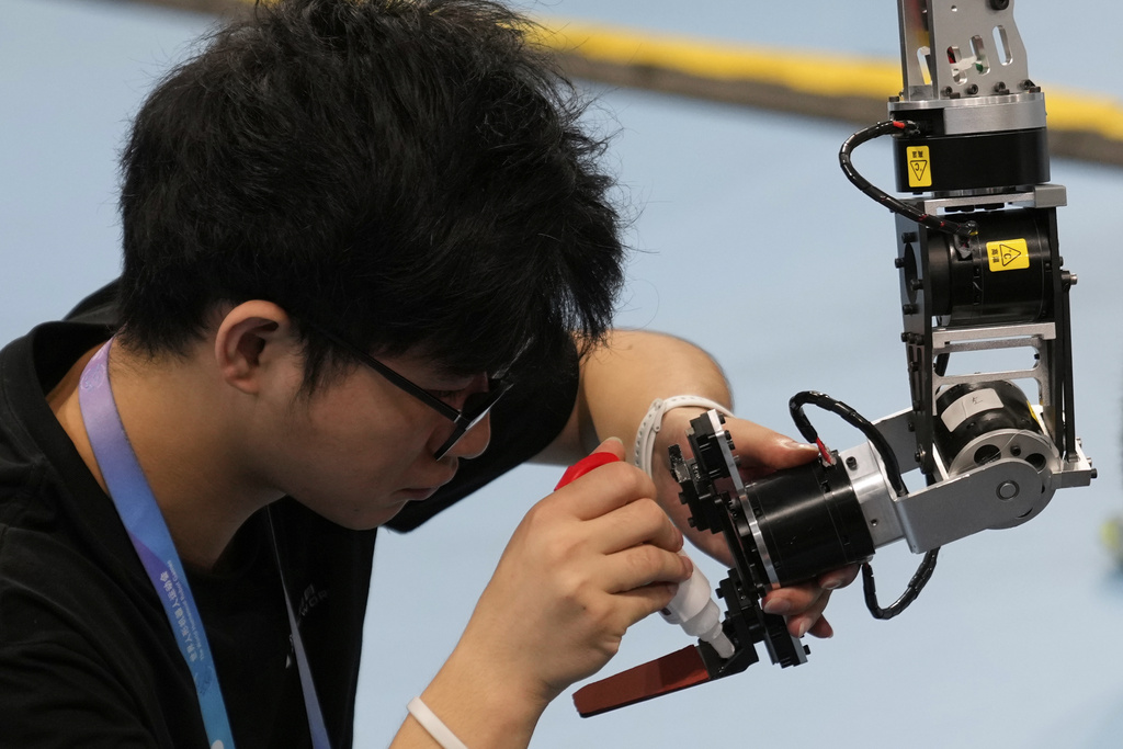 A technician fixes the arm of a robot during the World Humanoid Robot Games held in Beijing, China, Saturday, Aug. 16, 2025. (AP Photo/Mahesh Kumar A.)