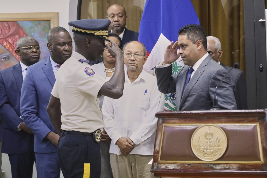 Newly-appointed police chief Vladimir Paraison, left, salutes Transitional Council President Laurent Saint-Cyr, during his presentation ceremony as the new interim police chief, in Port-au-Prince, Haiti, Friday, Aug. 8, 2025. (AP Photo/Odelyn Joseph)