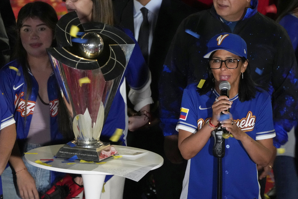 Venezuela's acting President Delcy Rodriguez, right, speaks next to the World Baseball Classic trophy a day after her team's victory over the United States in the championship match, at Miraflores presidential palace in Caracas, Venezuela, Wednesday, March 18, 2026. (AP Photo/Ariana Cubillos)