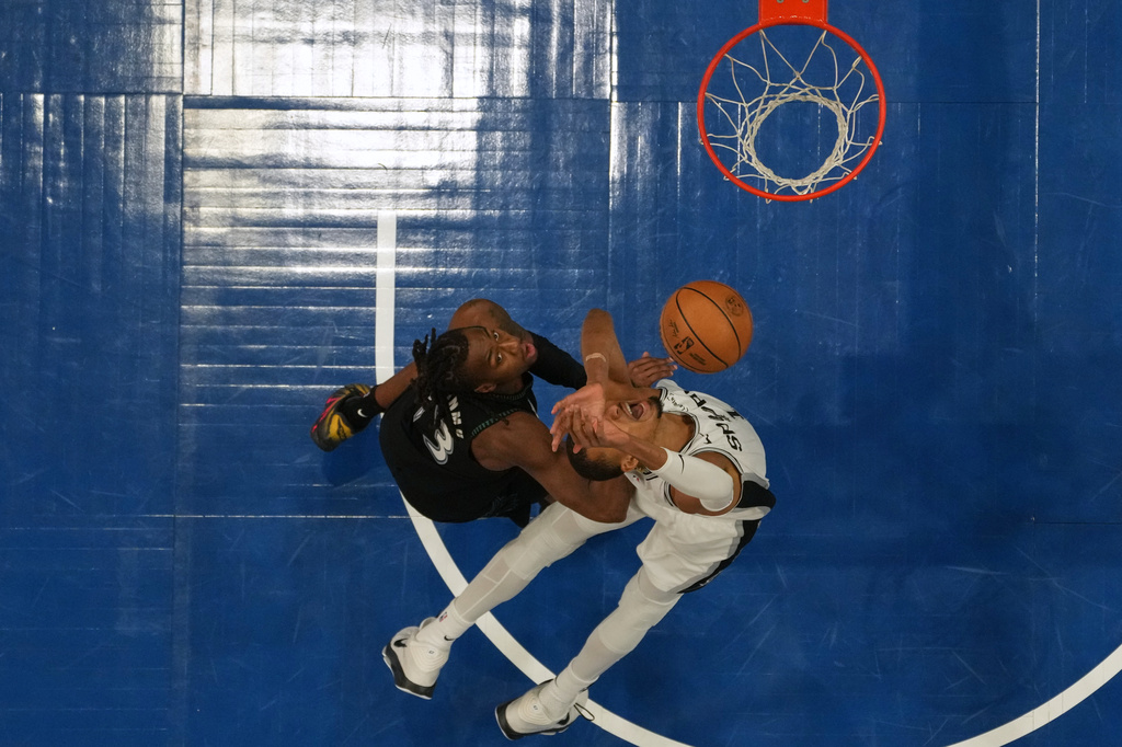 Minnesota Timberwolves guard Ayo Dosunmu, left, and San Antonio Spurs forward Victor Wembanyama reach for a rebound during the first half of Game 4 of an NBA basketball second-round playoffs series, Sunday, May 10, 2026, in Minneapolis. (AP Photo/Abbie Parr)