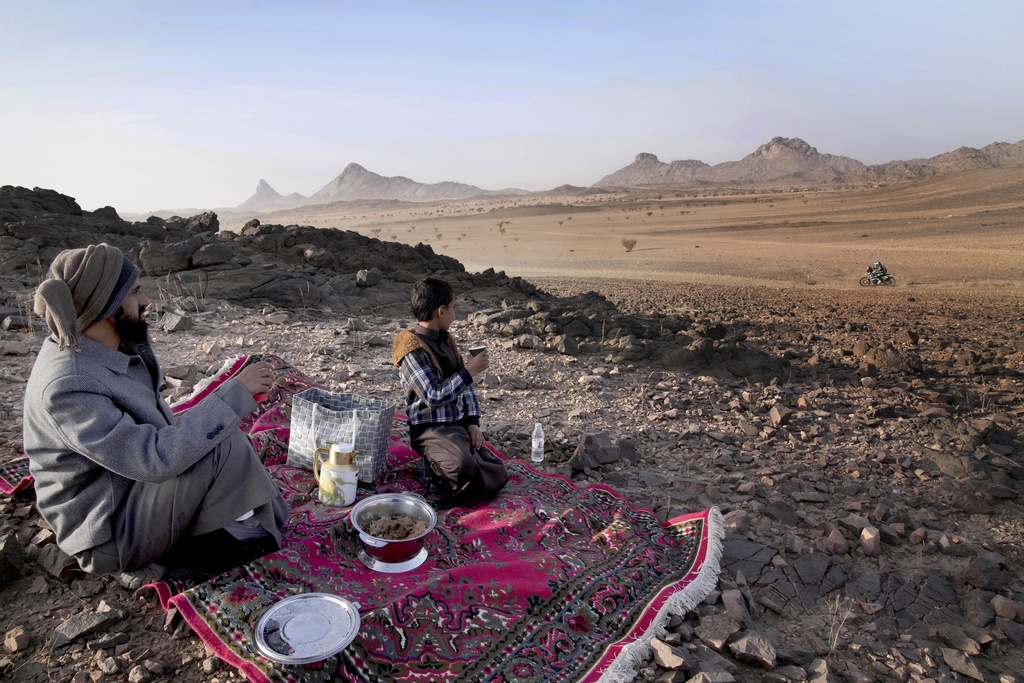 A man and his son watch the riders during the prologue of the Dakar Rally in Bisha, Saudi Arabia, Friday, Jan. 3, 2025. (AP Photo/Christophe Ena)