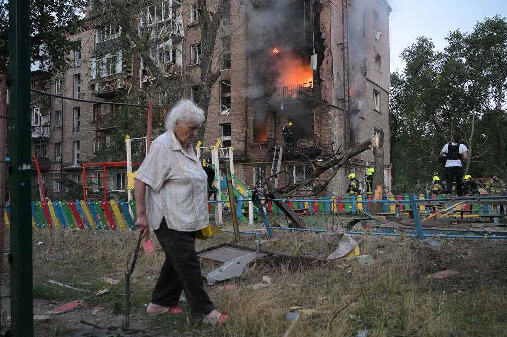 A woman walks past a burning apartment building after a Russian missile attack in Kyiv, Ukraine, Thursday, July 2, 2026. (AP Photo/Danylo Antoniuk)