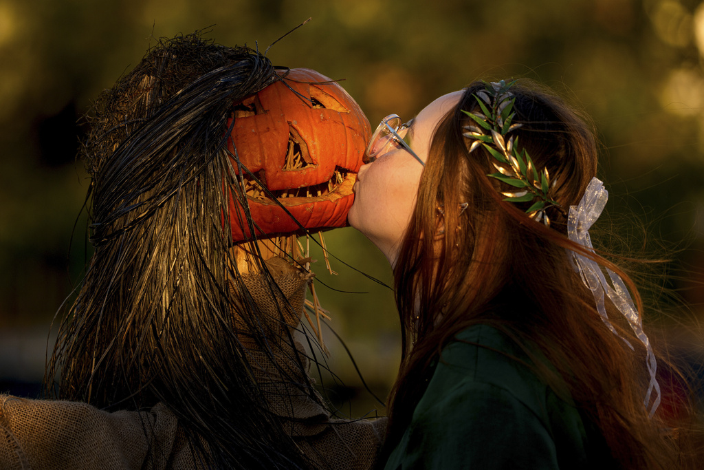 A girl poses for a friend while kissing a pumpkin at the West Side Hallo Fest, the country's largest Halloween festival in Bucharest, Romania, Friday, Oct. 24, 2025. (AP Photo/Andreea Alexandru)