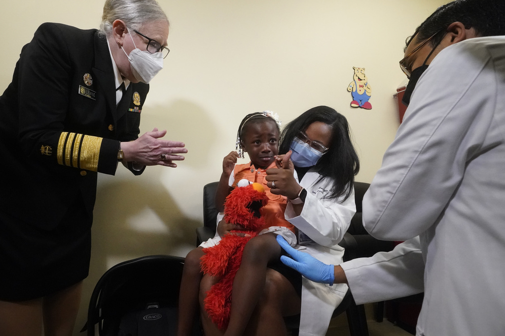 FILE - Department of Health and Human Services Assistant Secretary for Health, Admiral Rachel Levine, left, claps after Dr. Nizar Dowla, right, administered a vaccine, to Emiola Adebayo, 3, the daughter of fellow doctor Emy Jean-Marie, center, on June 28, 2022, at the Borinquen Health Care Center in Miami. (AP Photo/Wilfredo Lee, File)