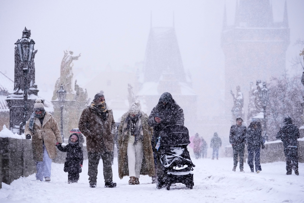 People cross the medieval Charles Bridge during a heavy snowfall in Prague, Czech Republic, Friday, Jan. 9, 2026. (AP Photo/Petr David Josek)