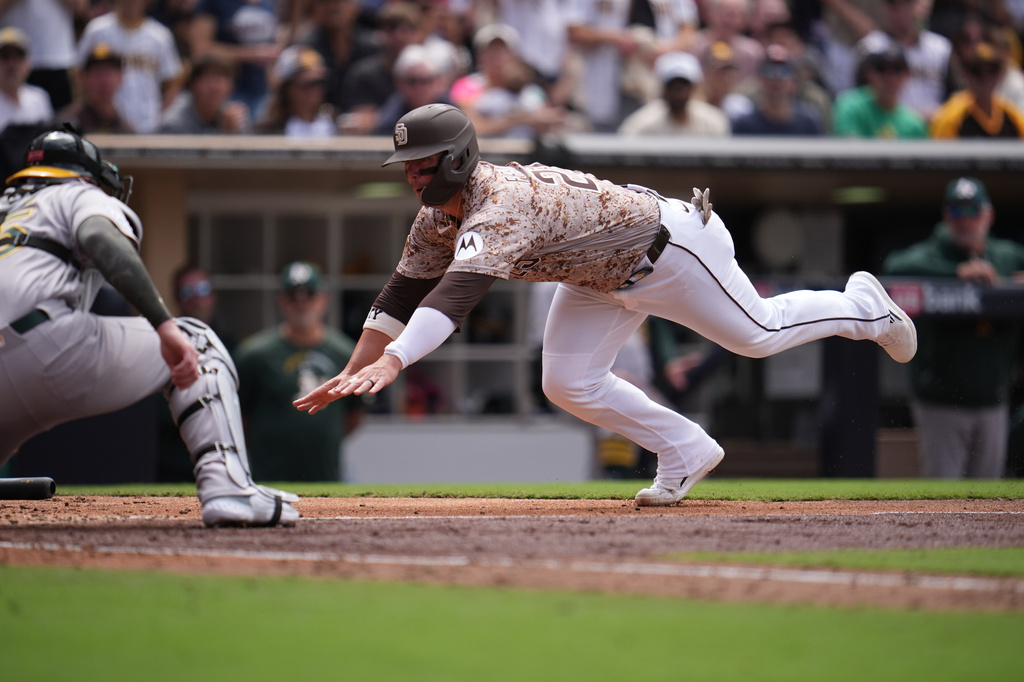 San Diego Padres' Ty France, right, slides into home before being tagged out by Athletics catcher Jonah Heim, let, as France was trying to score from first off a double by Fernando Tatis Jr. during the fifth inning of a baseball game Sunday, May 24, 2026, in San Diego. (AP Photo/Gregory Bull)