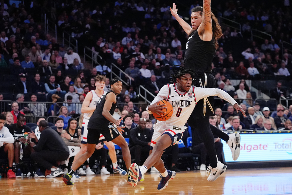 UConn's Malachi Smith (0) drives past Xavier's Tre Carroll (12) during first half of an NCAA college basketball game in the quarterfinals of the Big East basketball tournament Thursday, March 12, 2026, in New York. (AP Photo/Frank Franklin II)