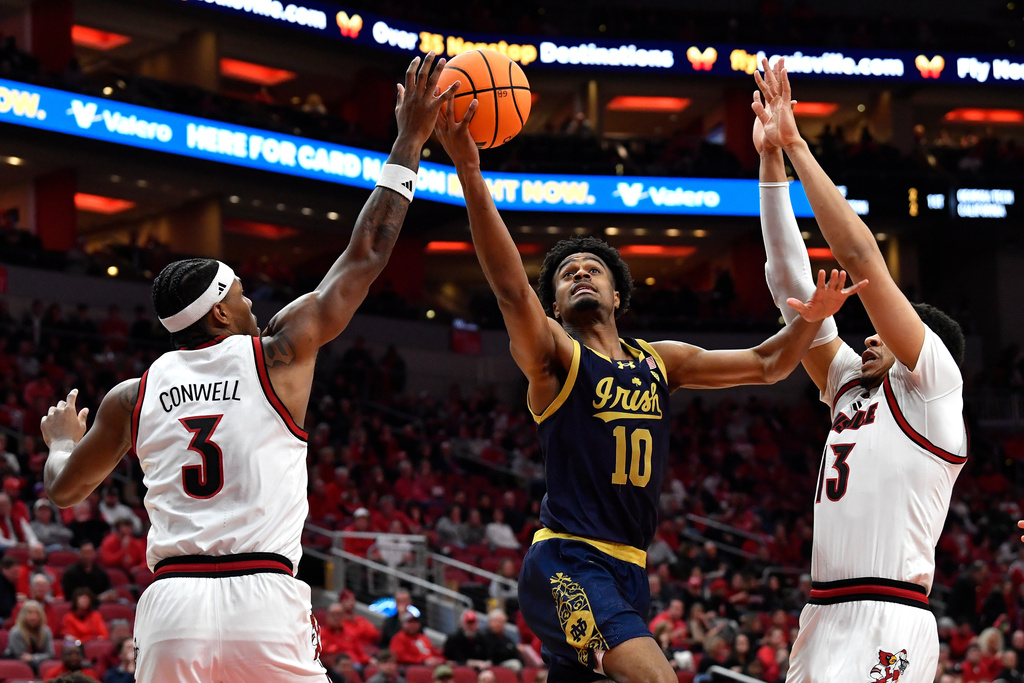 Notre Dame forward Jalen Haralson (10) attempts a shot between Louisville guard Ryan Conwell (3), and forward Sananda Fru (13) during the first half of an NCAA college basketball game in Louisville, Ky., Wednesday, Feb. 4, 2026. (AP Photo/Timothy D. Easley)