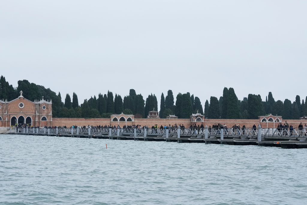 Mourners walk on the 'Votif' Bridge, a 407m temporary floating bridge connecting the city to the cemetery on the island of San Michele, to pay respects to their dead on All Soul's Day, in Venice, Italy, Sunday, Nov. 2, 2025. (AP Photo/Luca Bruno)