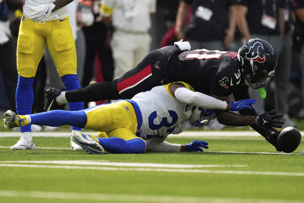 Houston Texans running back Dameon Pierce, top, reaches for the ball, which was ruled dead, over Los Angeles Rams safety Quentin Lake during the second half of an NFL football game, Sunday, Sept. 7, 2025, in Inglewood, Calif. (AP Photo/Mark J. Terrill)